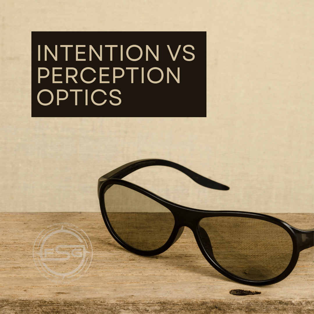 Intention vs perception optics sunglasses for FSG A pair of black sunglasses on the the edge of a table with a beige wall in the background. A brown rectangular bar with text inside that reads Intention VS Perception Optics. In the lower left corner is a watermark of the FSG logo in white. The logo has the letters FSG in the middle with a circle with four pointed arrows facing north, south, east and west with the S connected to that circle. Four rounded lines make the next circle of the circle and the last layer is a thin circle with the text on the Bottom that reads Stewarding Strategist Solutions and on top, the text reads Fish Stewarding Group.